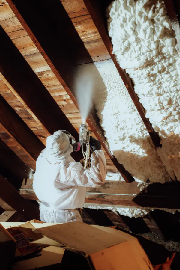 Patriot installer spraying foam onto attic rafters
